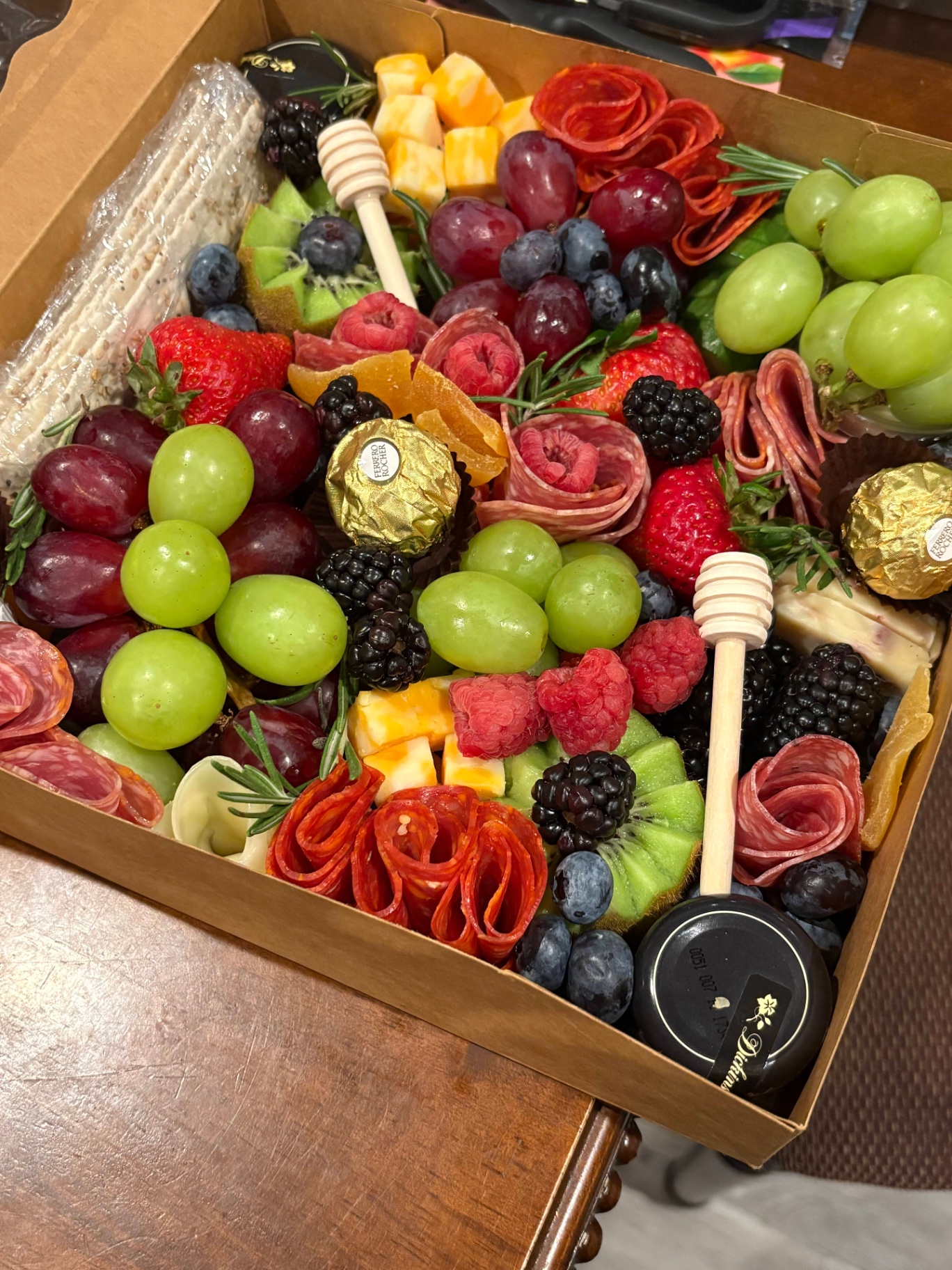 A luxury grazing box overflowing with fresh berries, cheeses, and cured meats